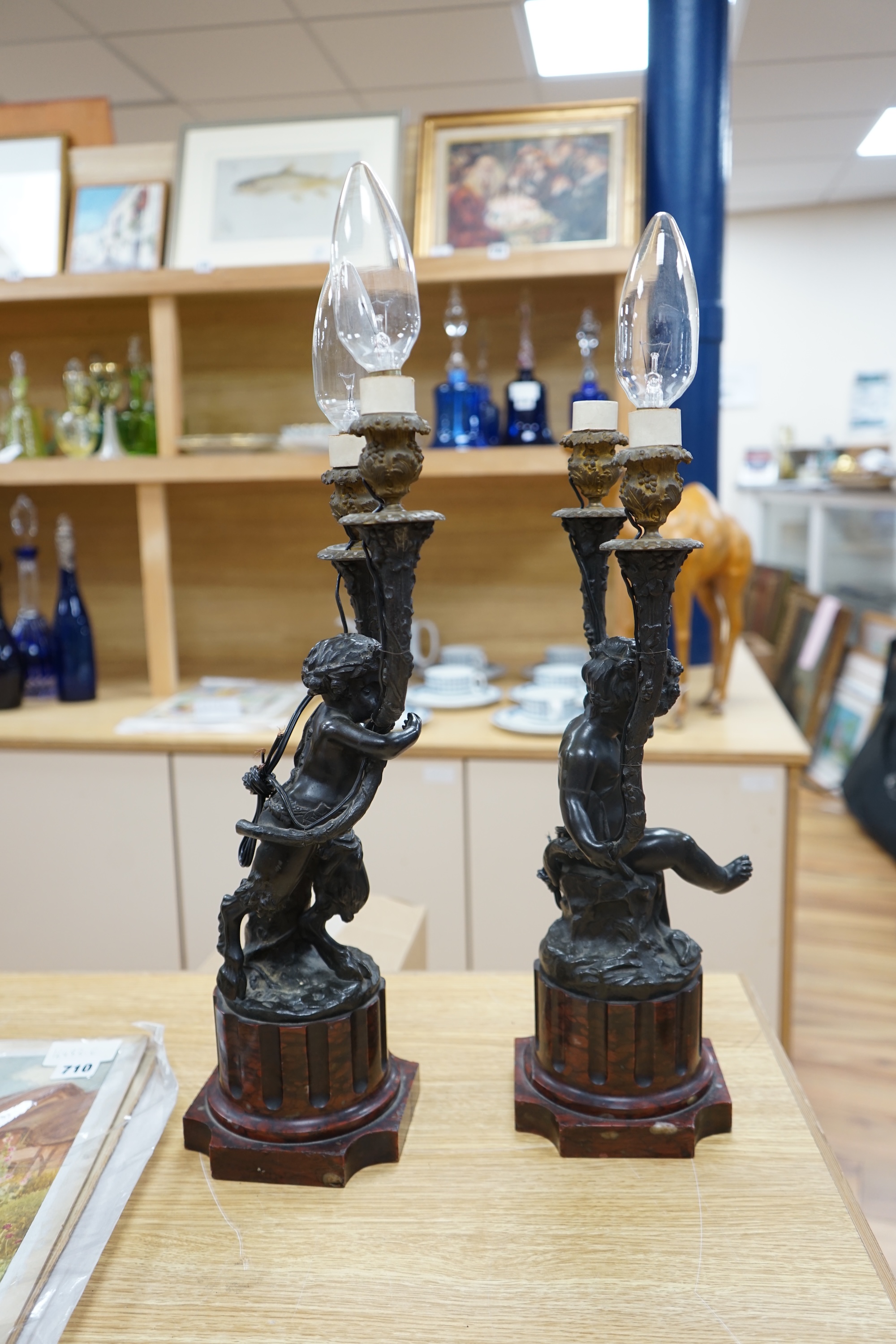 A pair of French bronze cupid twin candelabra with leaf shaped twin arms upon rouge marble fluted columns, after Clodion c.1840, 44cm high, excluding the fitting. Condition - fair